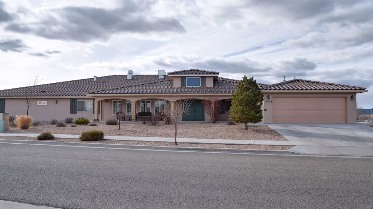 Single-story beige senior living home with a two-car garage and desert landscaping.