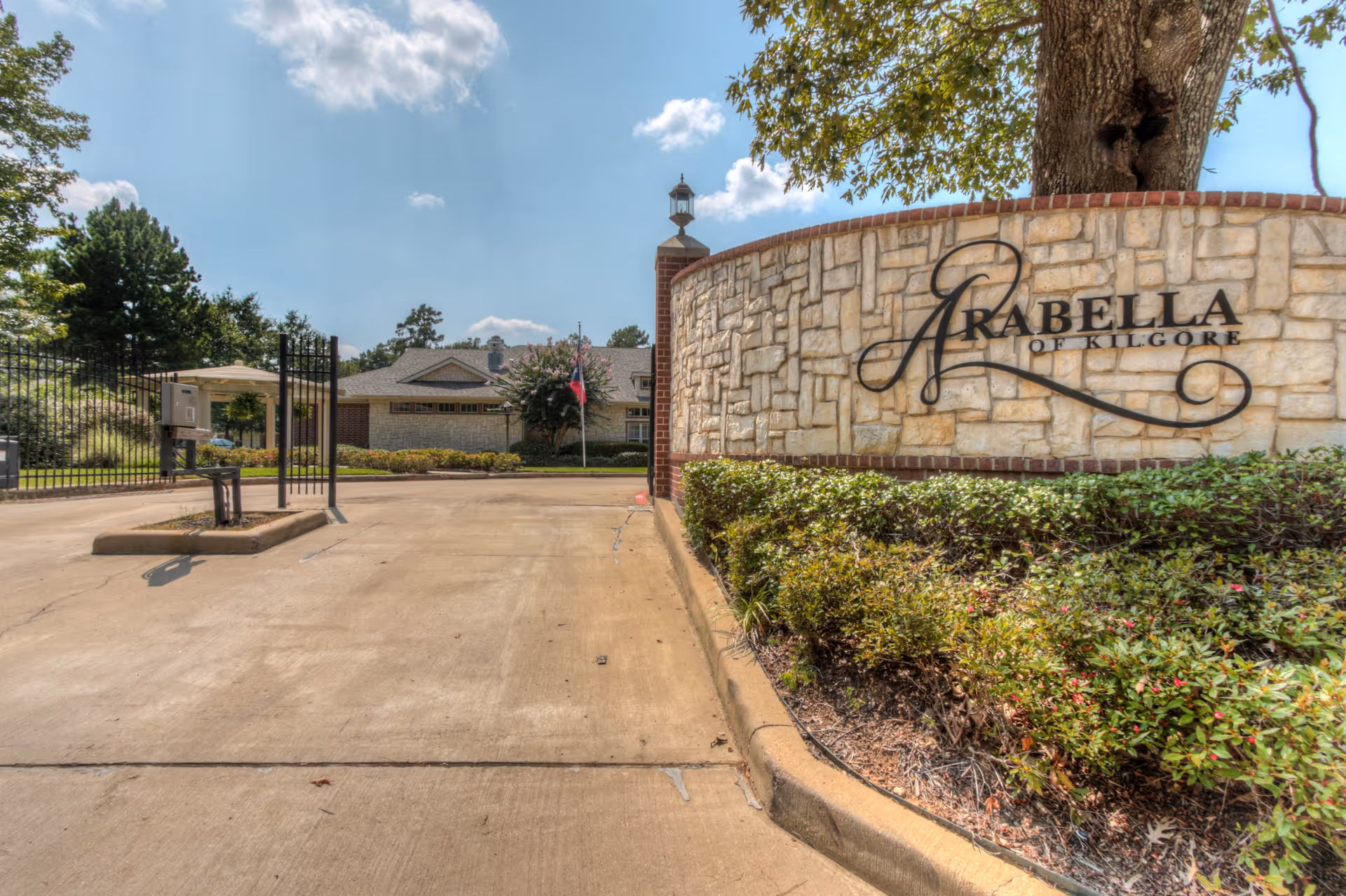 Entrance to Arabella of Kilgore Senior Living facility with a stone wall and gate.