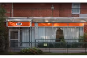 Brick building with orange awnings and large windows outside Morris Park Rehabilitation & Nursing Center.