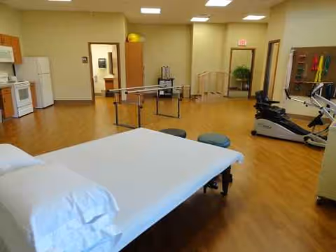 Therapy room inside United Pioneer Home with bed, parallel bars, and exercise equipment.