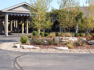 Front view of Brookdale Zanesville entrance with landscaping and trees lining the walkway.