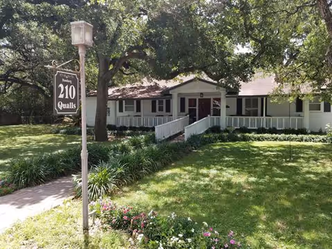 Single-story assisted living building with a front porch, ramp, and well-kept lawn.