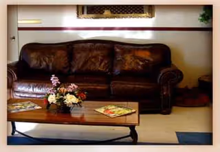 Dark brown leather sofa with flower arrangement and coffee table in a cozy living room.