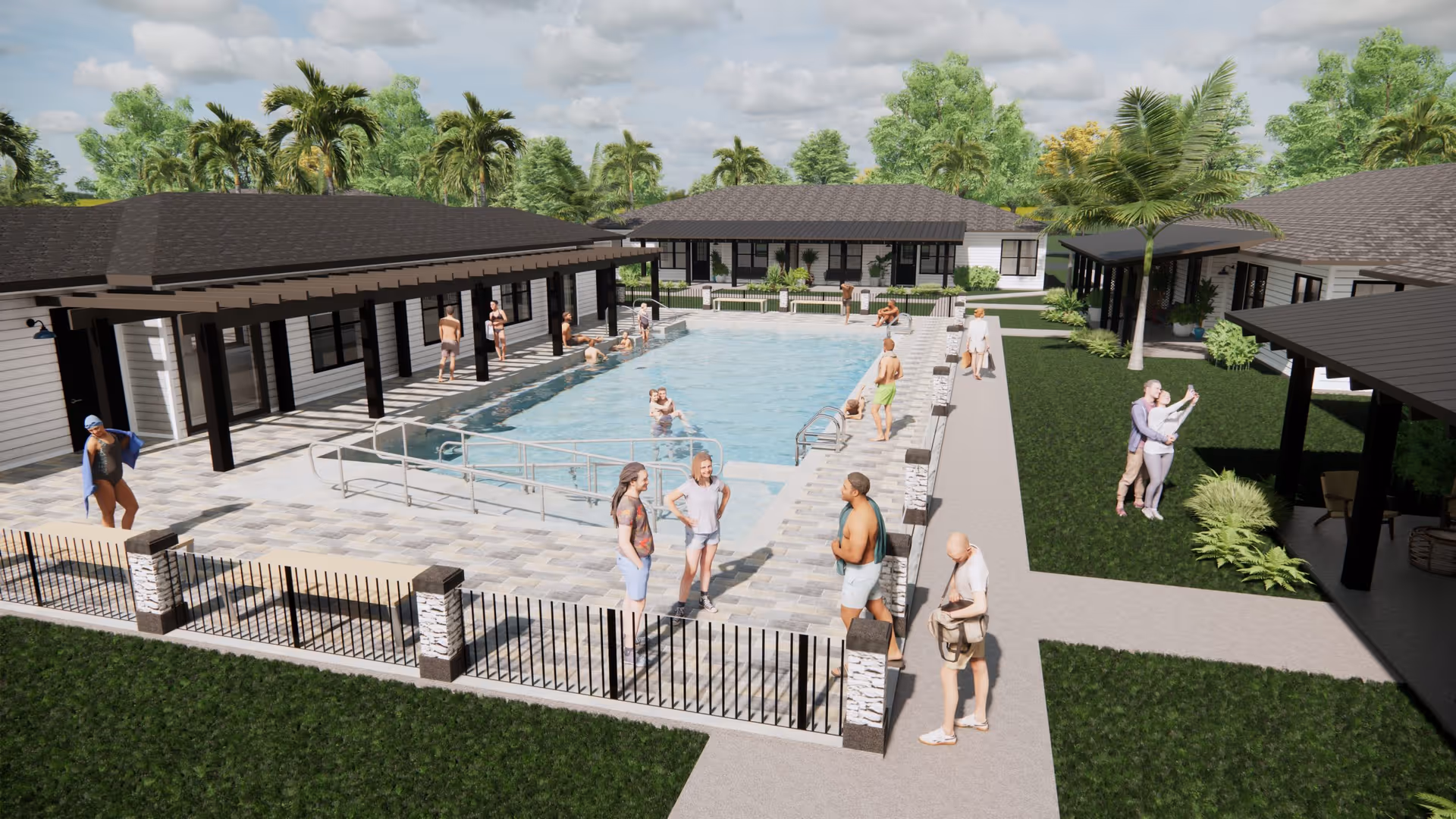 Outdoor swimming pool area at a senior living facility with several people standing, sitting, and swimming. The pool is surrounded by a paved deck and fenced with black metal railings. There are single-story buildings with covered walkways around the pool, palm trees, and green lawns under a partly cloudy sky.