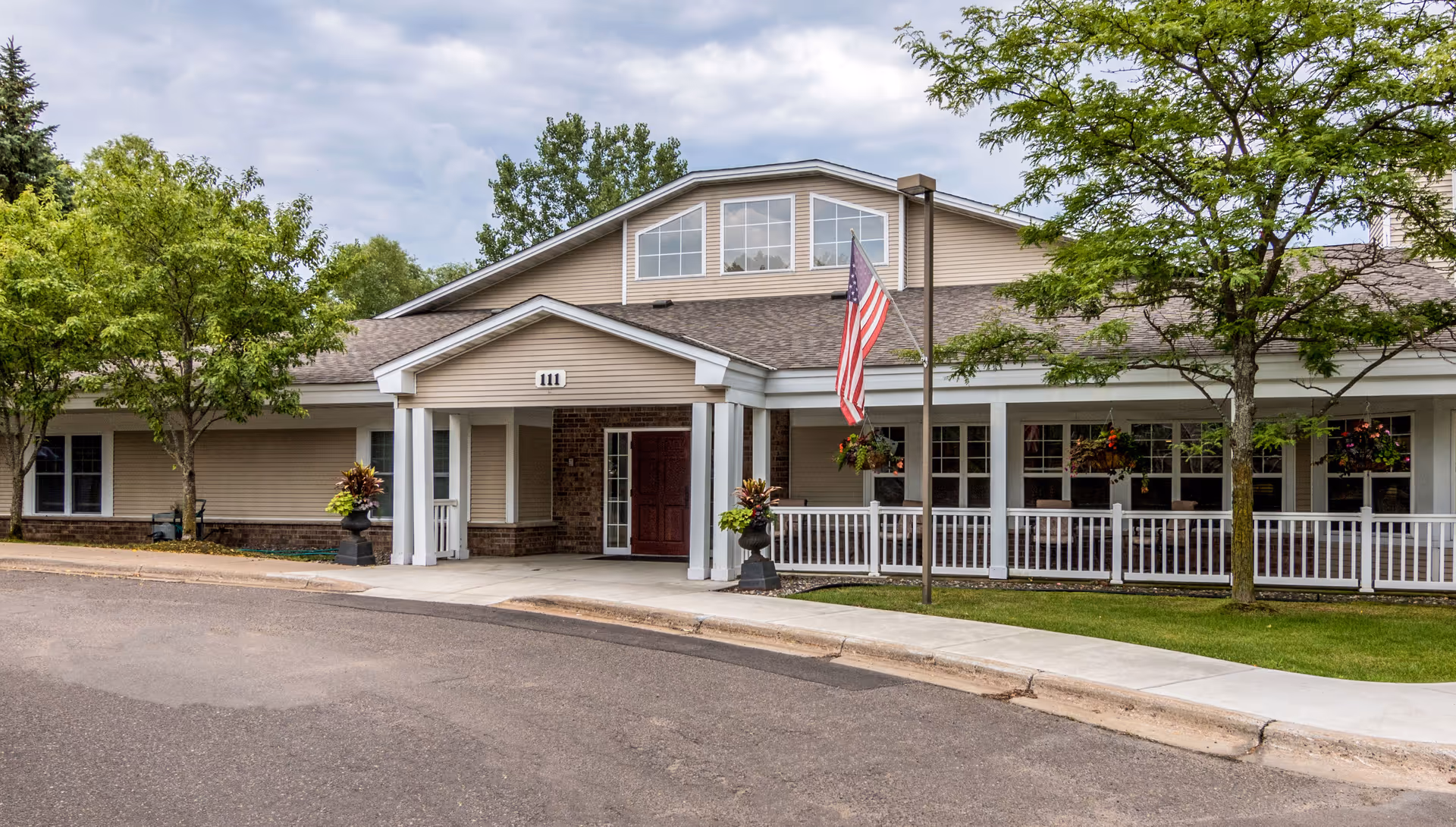 Front exterior of New Perspective Mahtomedi, showing entrance, flag, and landscaped walkway.
