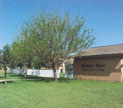 Exterior view of Westridge Manor with green lawn, trees, and building sign.