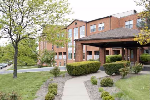 Brick senior living facility with entrance canopy and landscaped walkway.