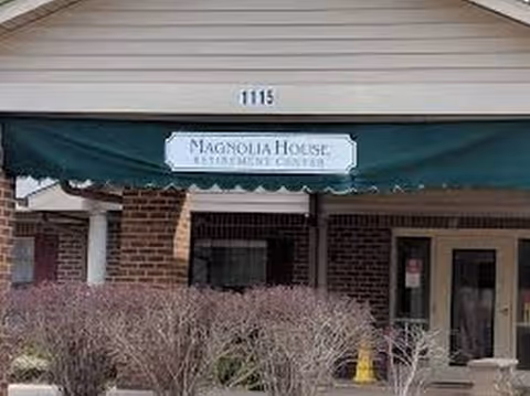 Front entrance of Magnolia House Memory Care with brick building and green awning at 1115.