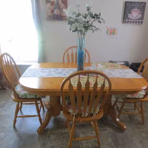 Wood dining table with chairs and a vase in a bright dining room