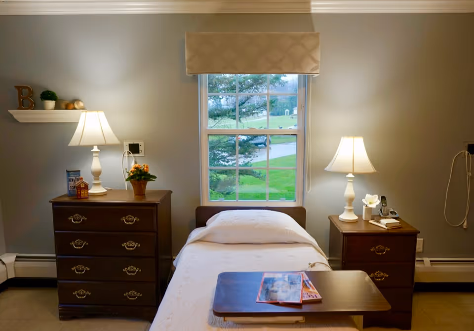 A tidy single bedroom with a bed centered under a window flanked by two nightstands and lamps.