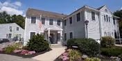 Front view of Pine Rock Manor senior living facility with walkway and landscaped garden.