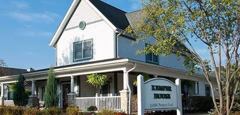 White two-story senior living facility with a covered porch and Kemper House sign.