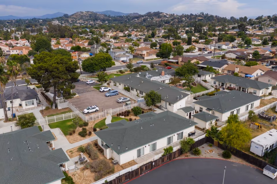 Aerial view of a single-story senior living complex with multiple buildings, parking areas, and surrounding residential neighborhood.