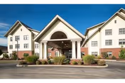 Front exterior view of Presbyterian SeniorCare Network - Southmont building with a covered entrance, landscaped bushes, and a clear sky.