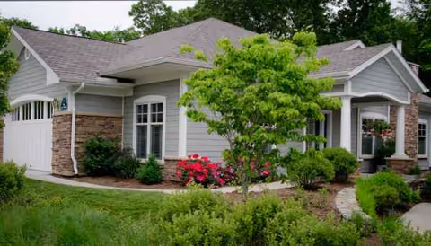 Exterior view of a single-story, house-style senior living facility with landscaped front yard.