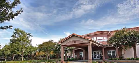 Front exterior view of Magnolia Court Senior Assisted Living showing entrance, columns, and trees.