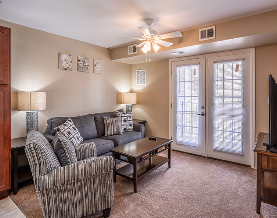 Cozy living room in a senior facility with sofa, chairs, lamps, and French doors.