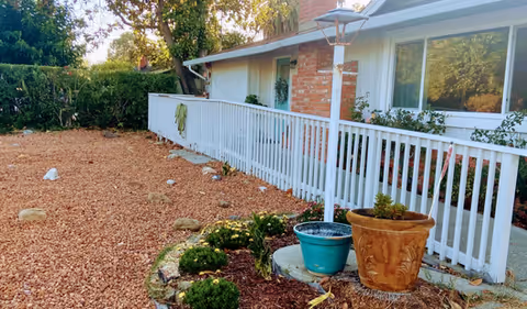 Exterior view of Windermere at Whitman with white railing, gravel yard, and potted plants.