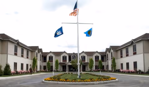 Exterior view of Braemar at Medford with a circular driveway and flags.