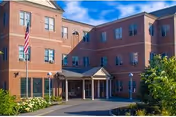 Exterior of Mount St Joseph Nursing Home: brick building, entrance canopy, flag, and landscaping.