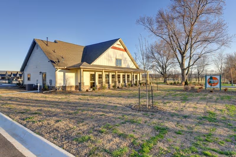 Exterior view of Cedar Springs Independent Living building with a front porch, lawn, and sign.
