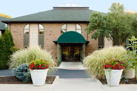Entrance of Brookdale Gardens at Westlake, brick building with green awning and decorative planters.