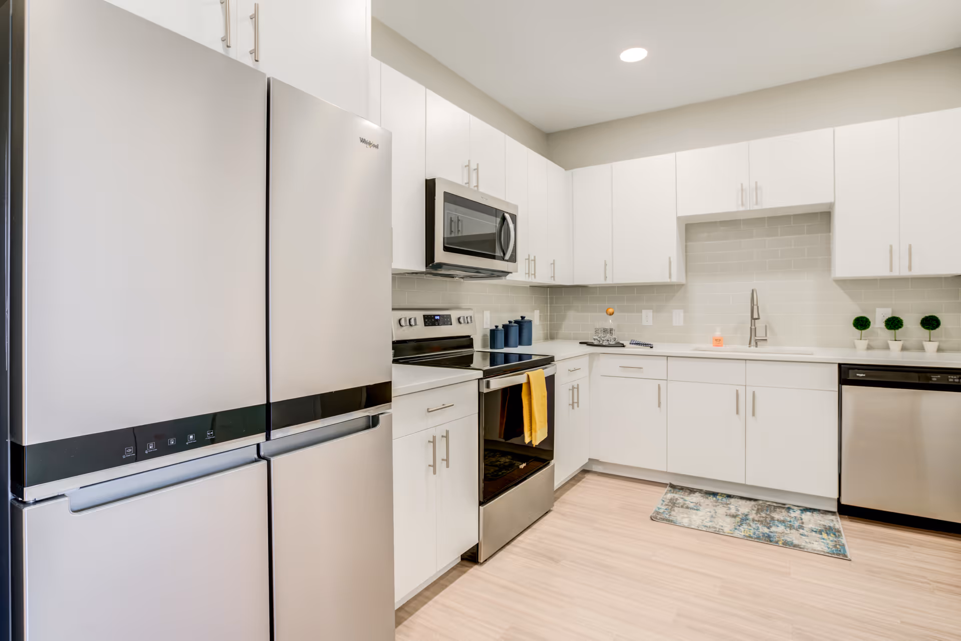 Modern kitchen with stainless steel appliances, white cabinets, and a subway tile backsplash.