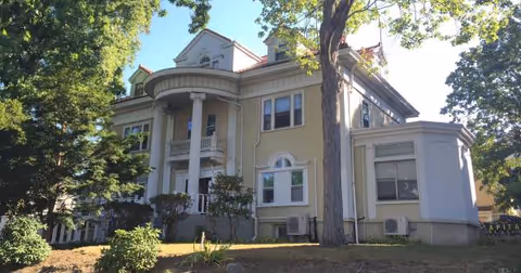 Exterior view of Chester Hill Adult Home building with columns and trees