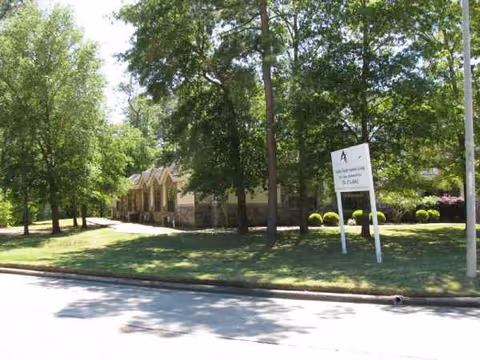 Exterior view of Parsons House Cypress with a tree-lined lawn and sign along the street.