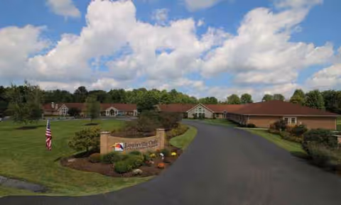 Exterior view of Altercare Louisville with driveway, sign, flag, and low-rise buildings.