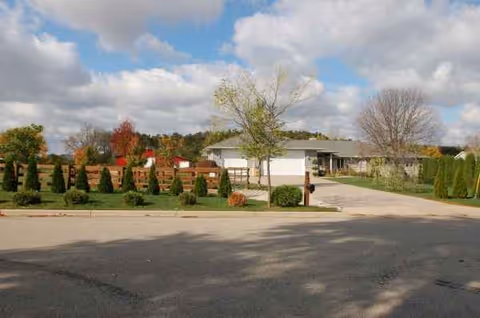 Front view of a single-story senior living facility with manicured landscaping and driveway.