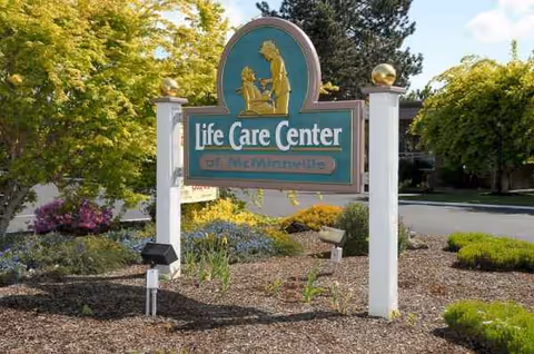 Life Care Center of McMinnville entrance sign amid landscaped garden beds