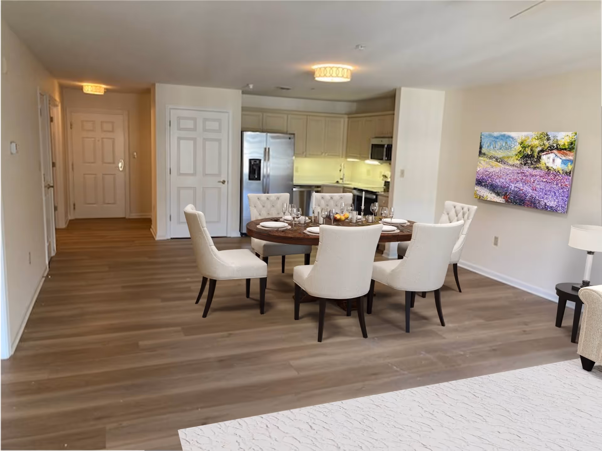 Open-plan dining area with a round table set for six and upholstered chairs in front of a kitchen.