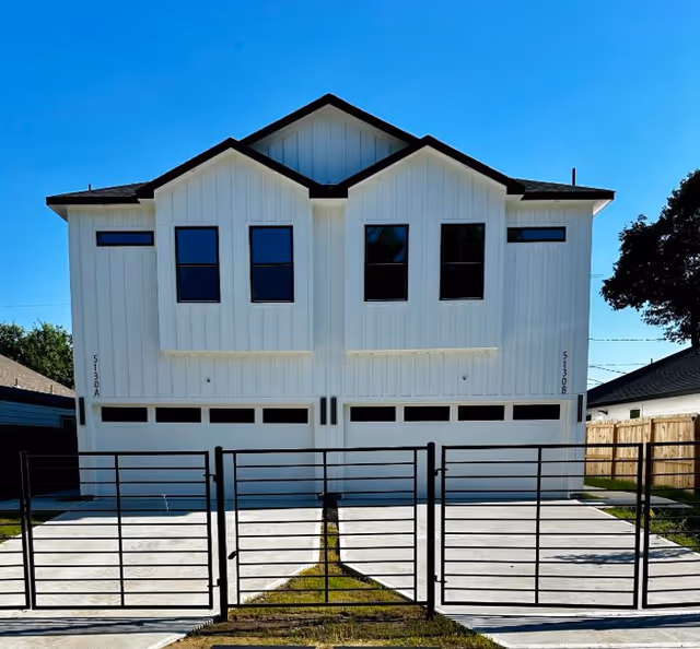 White two-story building with black metal gate and garage doors at Pegasus Landing.