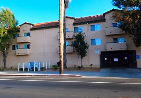 Exterior view of a beige senior living building with balconies and a driveway.