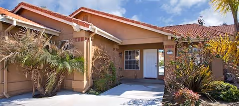 Front exterior of a single-story senior living home with a tiled red roof.