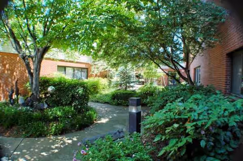 St. Mary's Nursing Center courtyard with trees, shrubs, and a winding walkway.