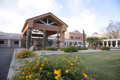 Exterior of a senior living facility with porte-cochere and landscaped flower beds.
