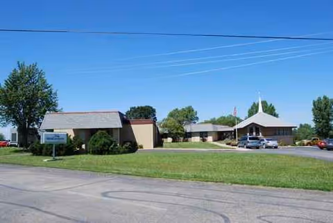Front view of Medicalodges of Jackson County facility with parking, lawn, and clear blue sky.