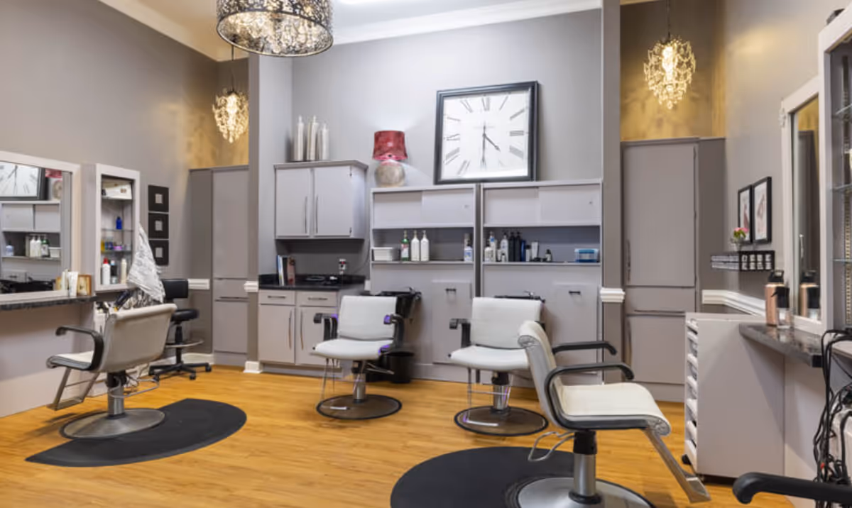 Interior salon styling area with multiple chairs, mirrors, cabinets, and a large wall clock.