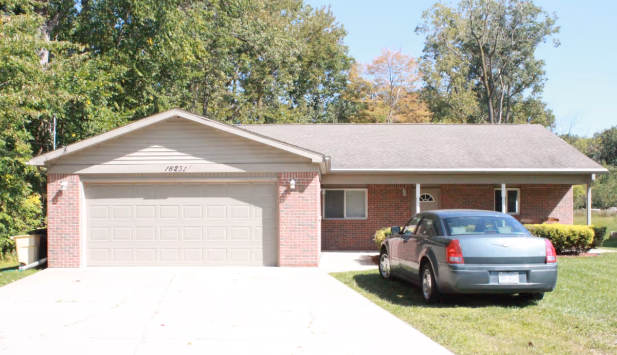 Single-story brick senior living facility with a two-car garage and a parked car.