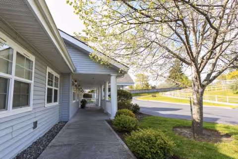 Exterior view of a senior living facility with a covered walkway and greenery