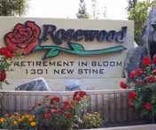 Exterior sign reading Rosewood Retirement Community with blooming flowers.