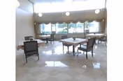 Bright dining room with multiple tables and chairs, large windows with valances, pendant lights, and a glossy checkered tile floor.