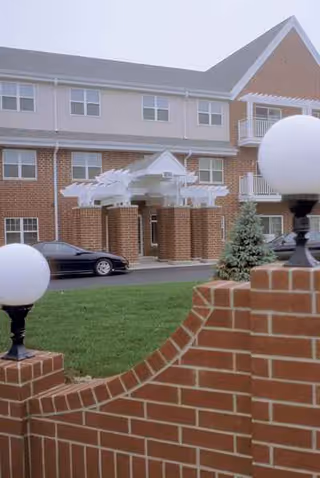 Exterior view of Parkside Commons Senior Apartments with brick facade, covered entrance, and landscaping.