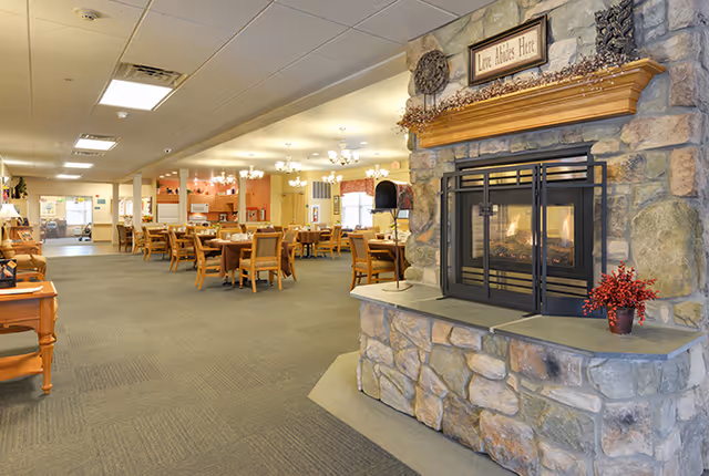 Spacious communal dining area with multiple tables and chairs and a stone fireplace in the foreground.