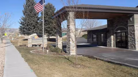 Front entrance of Pinnacle Nursing and Rehabilitation Center with a covered driveway and flag.