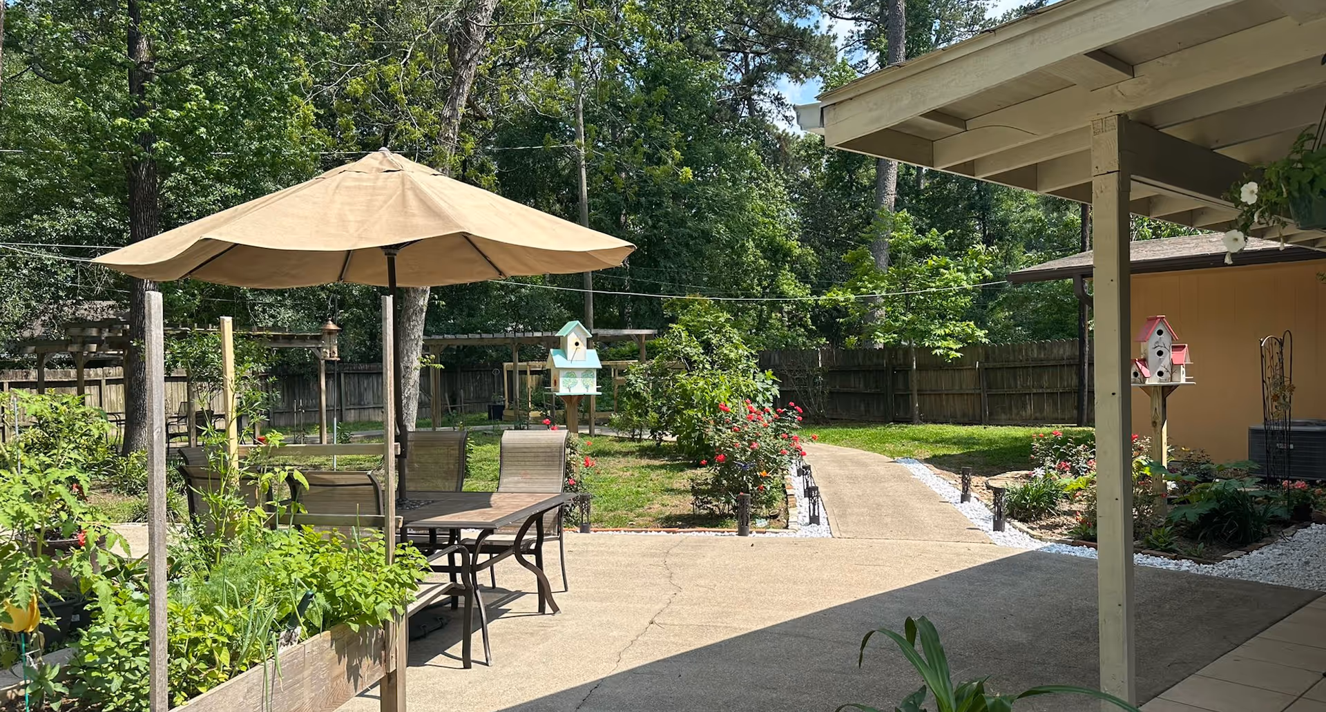 Outdoor patio with umbrella, chairs, garden, and walkway at Grace Family Care.